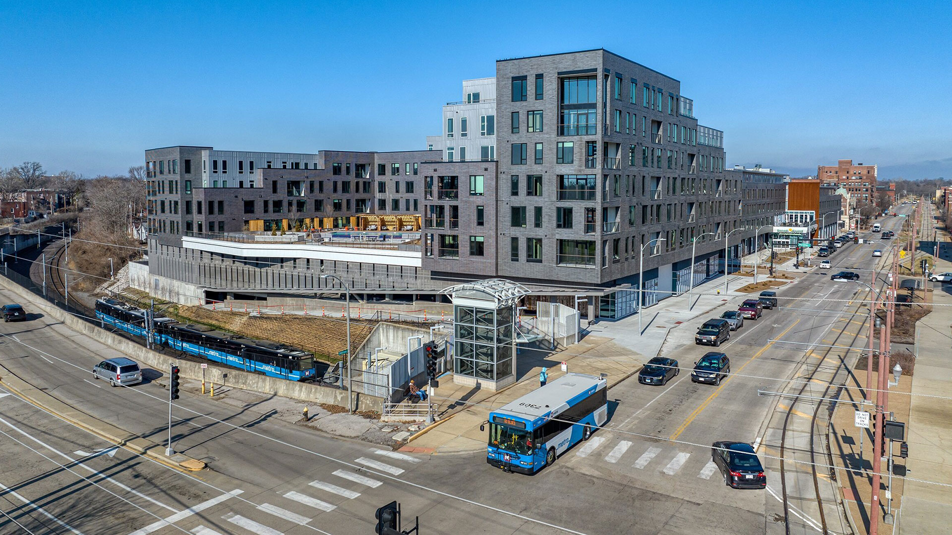 A Metro bus and train with newly constructed apartments in the background.